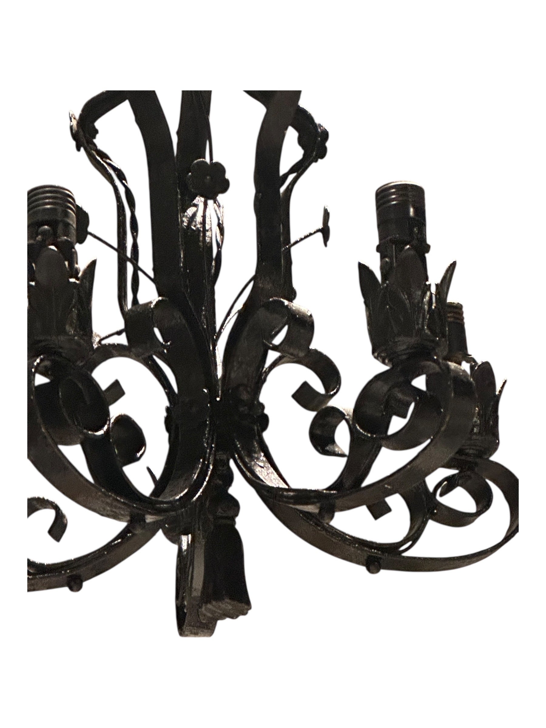 Wrought iron chandelier arm detail with leaf motif and bulb socket, close-up
