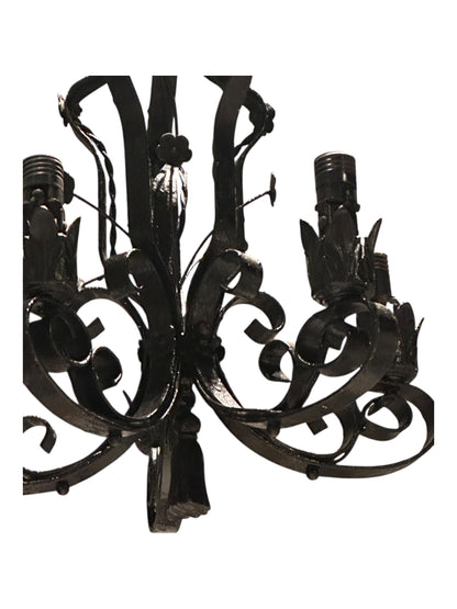 Wrought iron chandelier arm detail with leaf motif and bulb socket, close-up