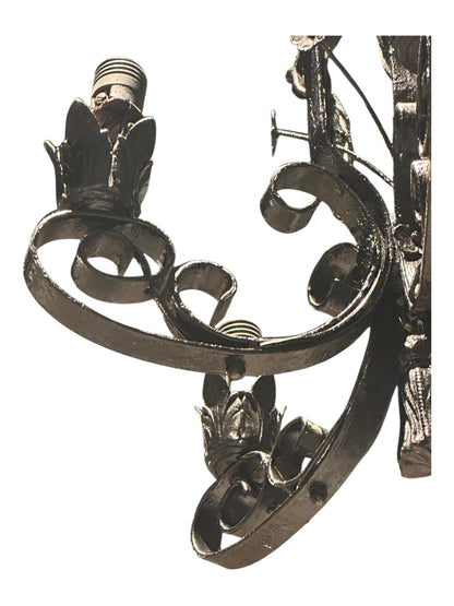 Underside detail of black wrought iron chandelier showing central tassel finial