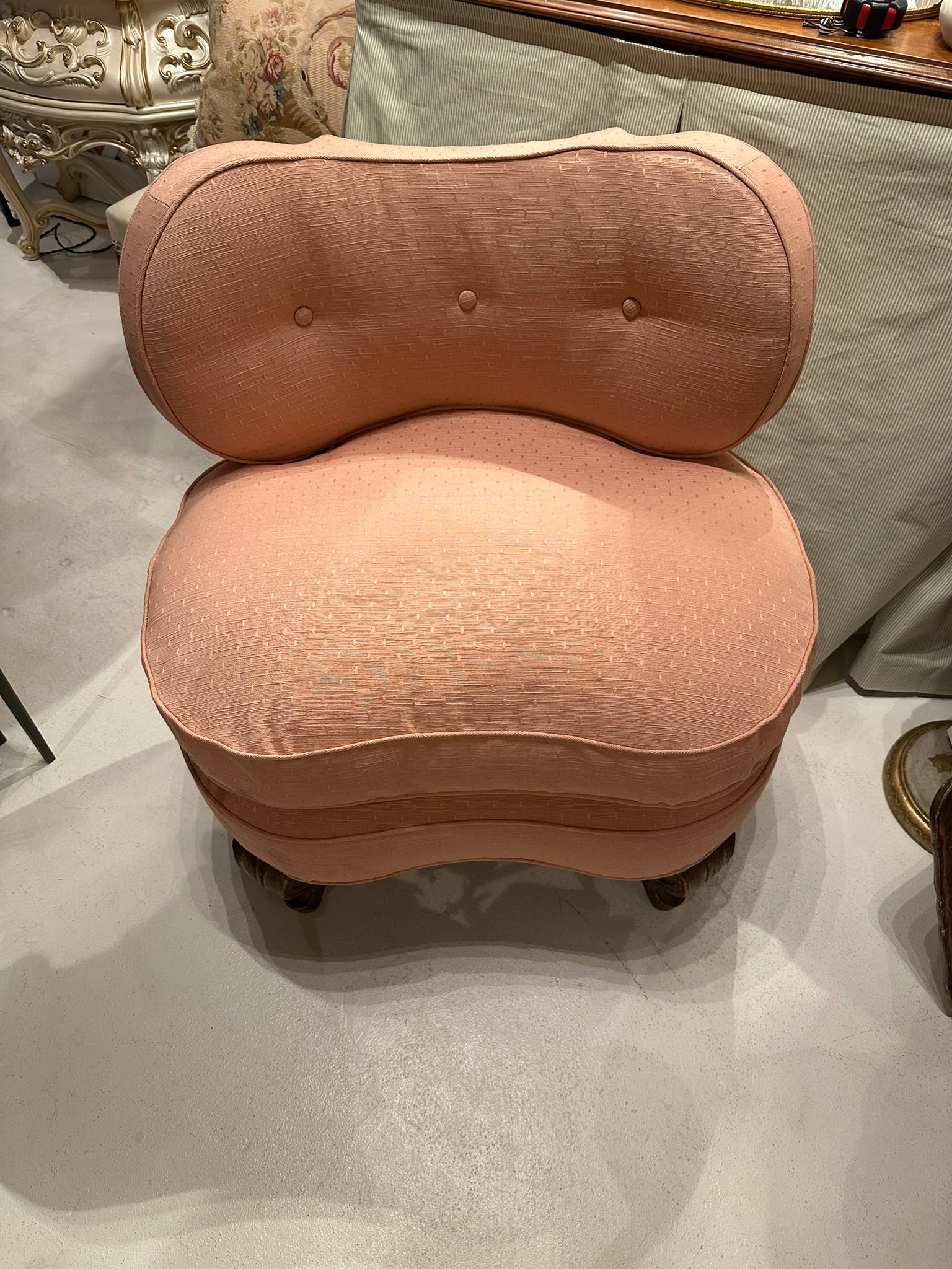 Antique pink coral boudoir chair, front view of tufted back and rounded seat in showroom