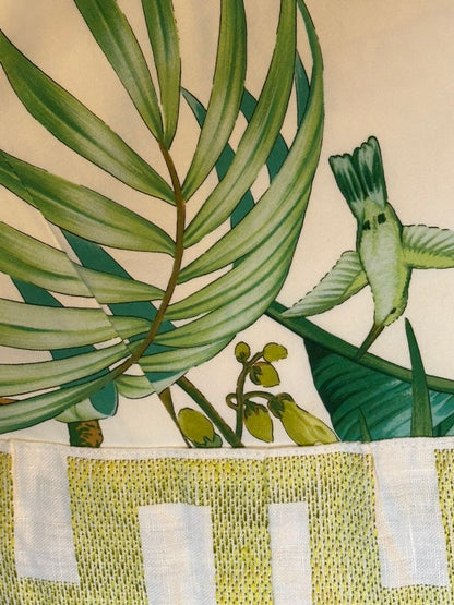 Brunschwig & Fils Anima tablecloth, close-up of palm fronds and hummingbird above green Greek-key border