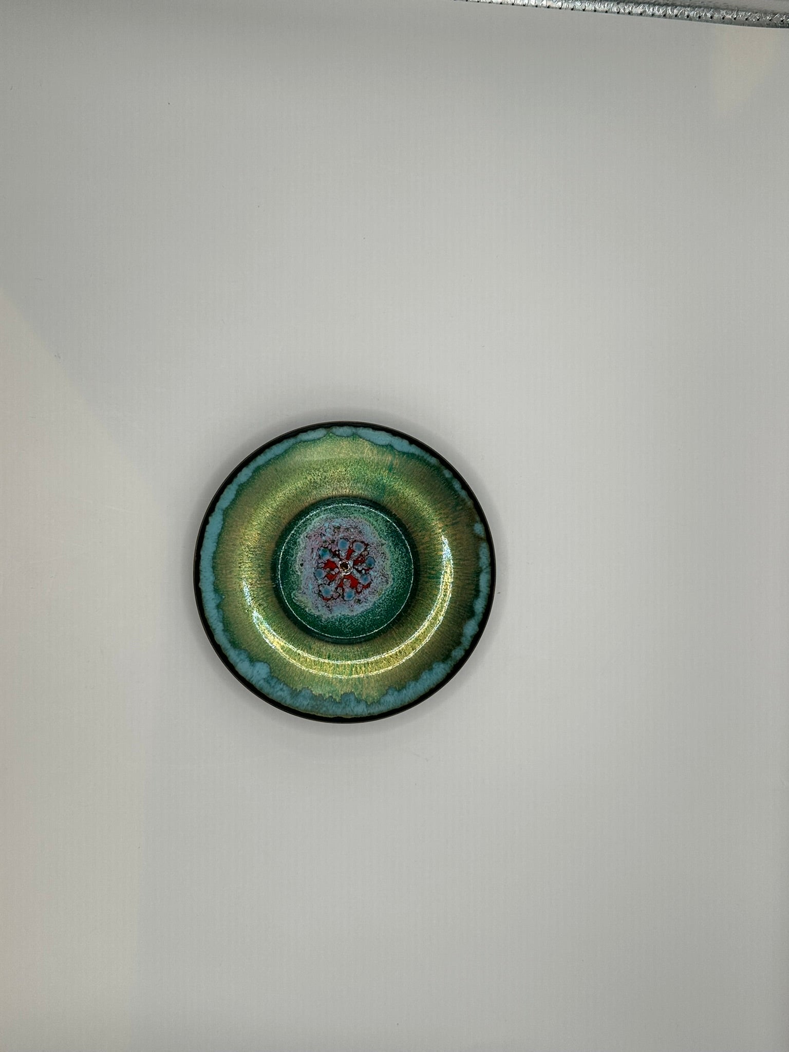 Doris Hall petite green enamel dish, top view with teal rim and red floral starburst center