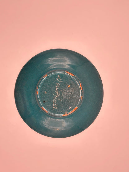 Underside of Doris Hall petite teal enamel dish on pink, signed 'Doris Hall' in white script
