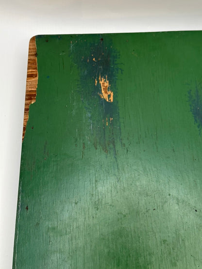 Underside of green wood tray showing worn green paint, scratches and exposed wood