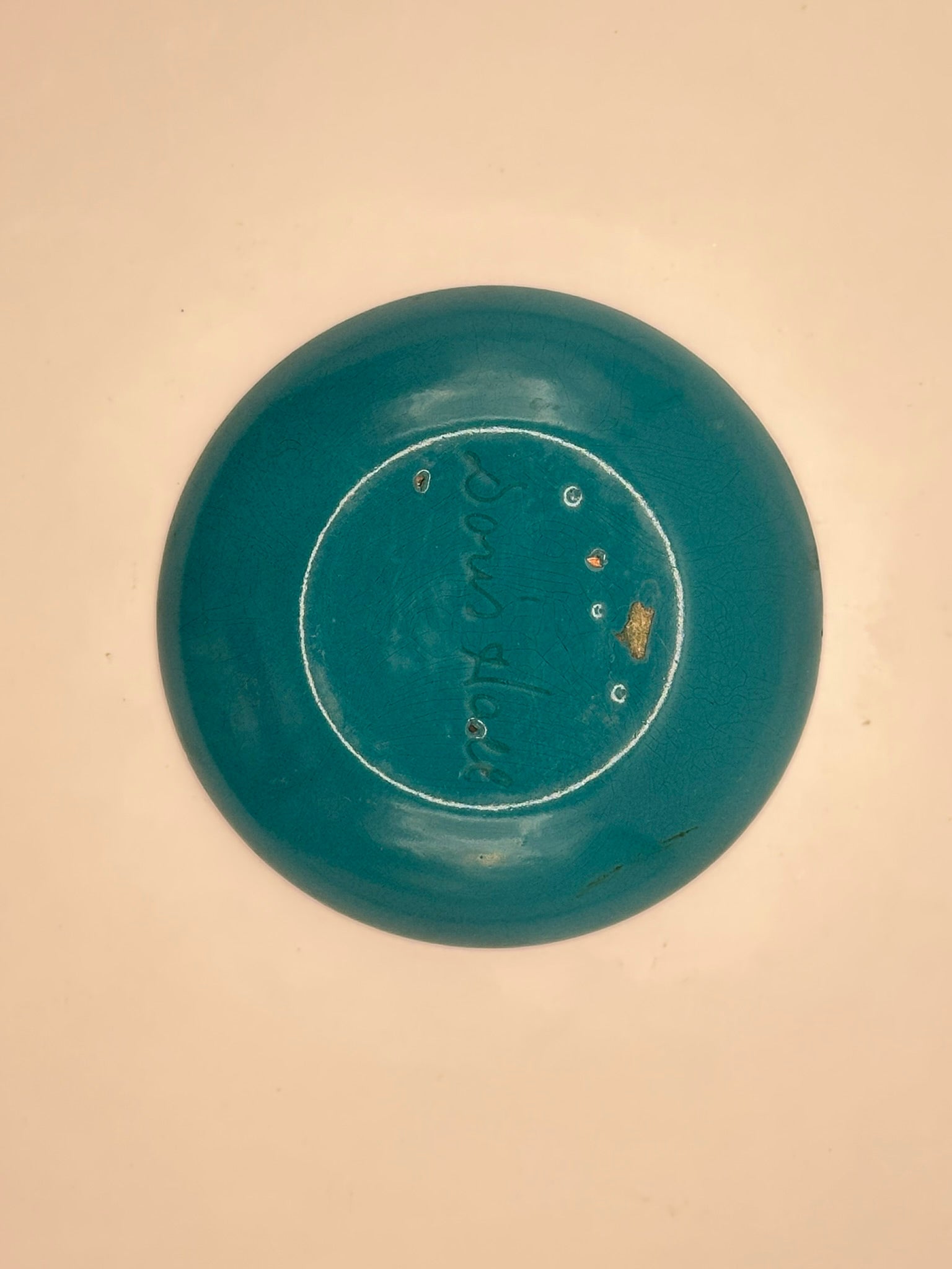 Close-up of Doris Hall enamel dish underside, teal enamel with engraved 'Doris Hall' mark