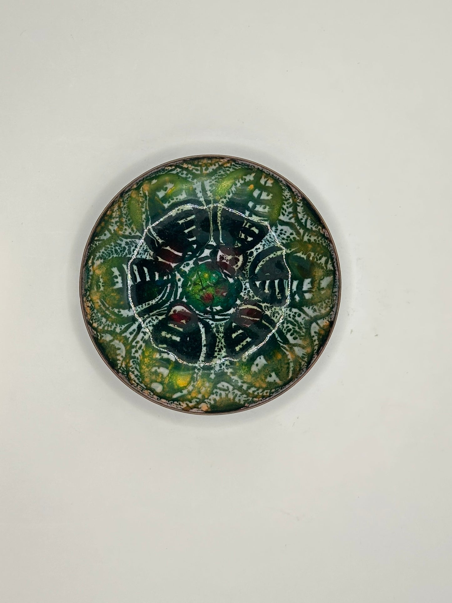 Top view of Doris Hall enamel-on-copper dish, dark green abstract floral motif