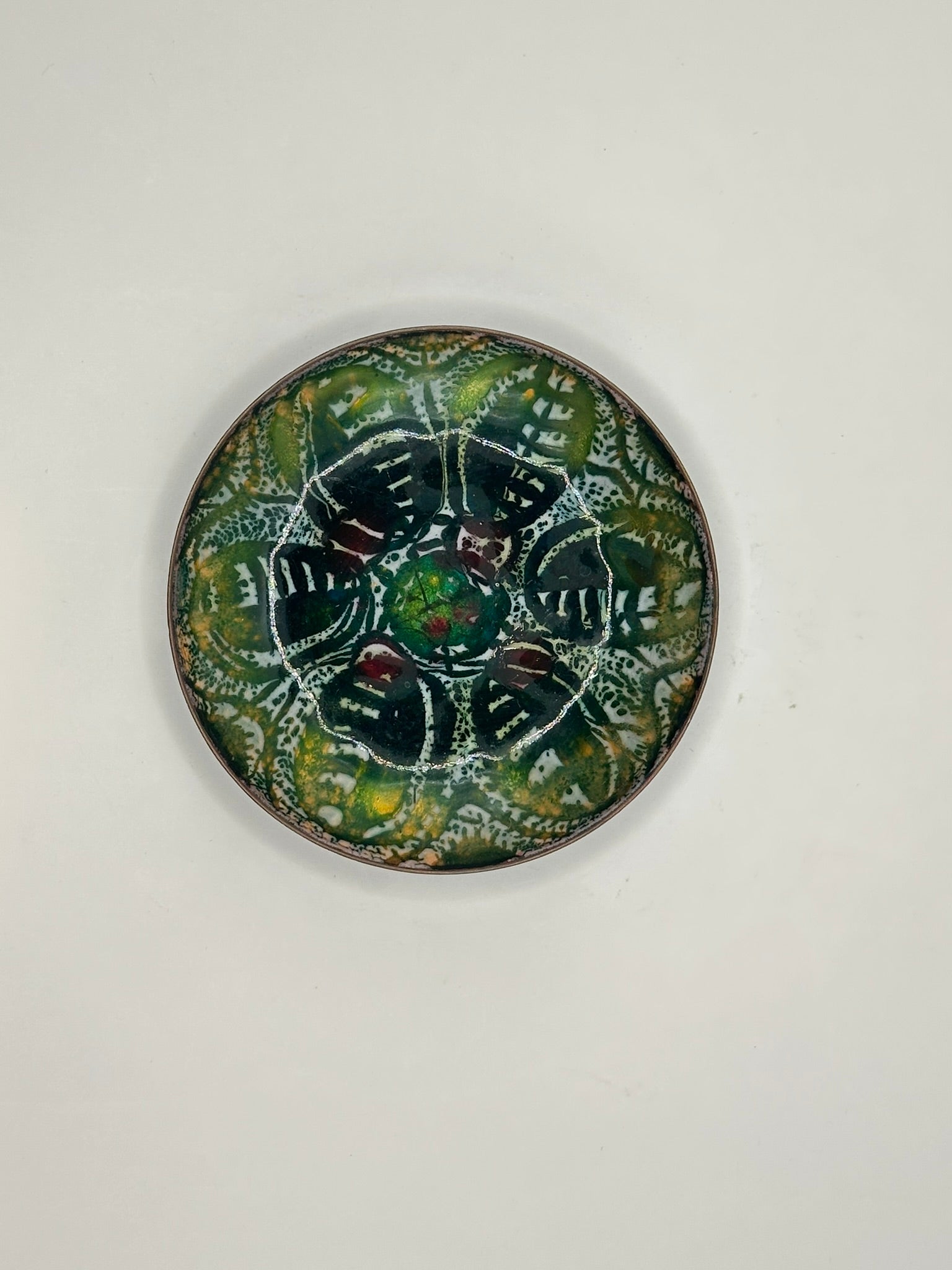 Top view of Doris Hall enamel-on-copper dish, dark green abstract floral motif