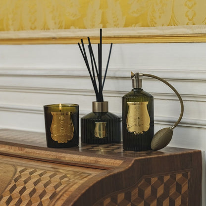 Trudon spray, candle and reed diffuser styled on an inlaid wood cabinet against a damask wall.
