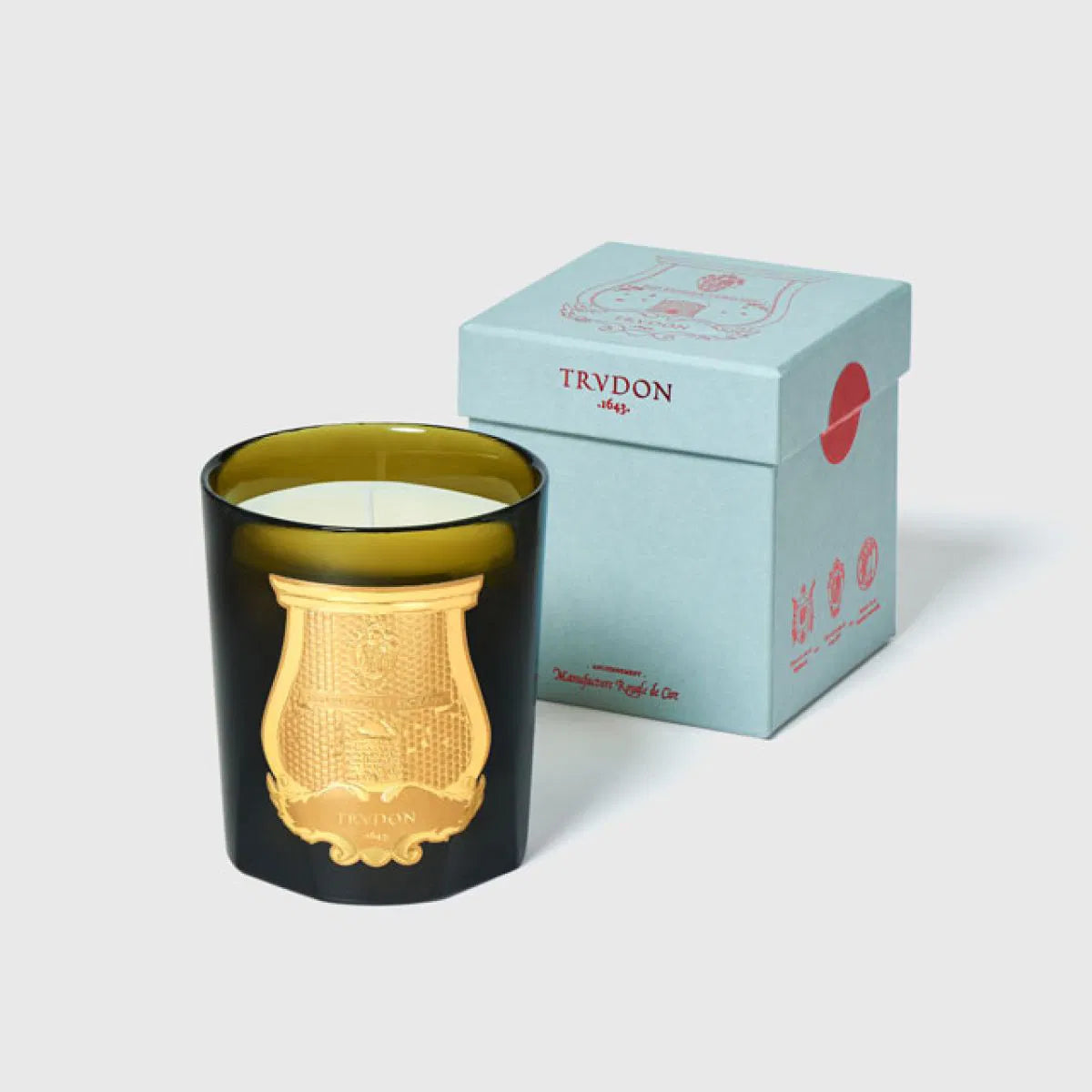 Olive green Trudon Classique candle beside a pale aqua gift box with red Trudon lettering