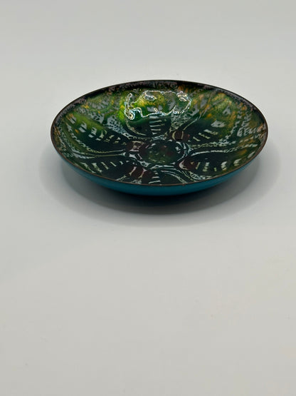Angled view of Doris Hall enamel-on-copper dish, green interior pattern over turquoise underside