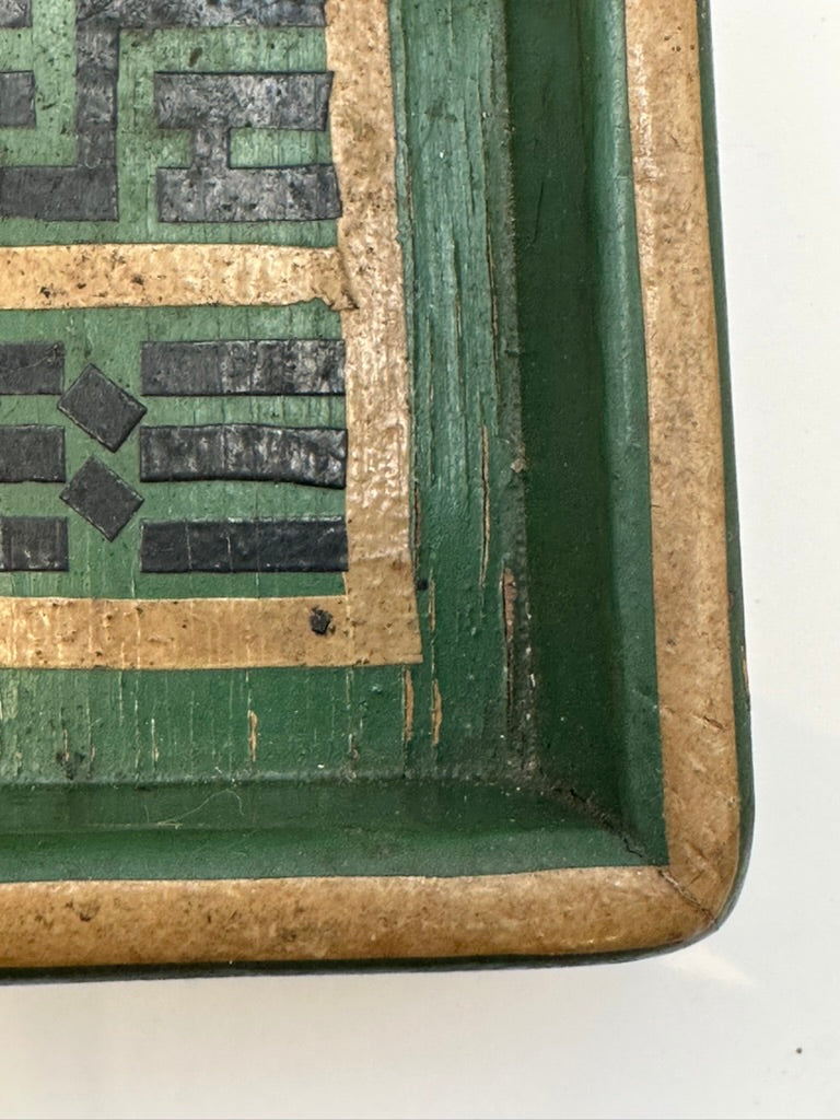 Corner detail of green wood tray showing geometric border and worn gilt edge