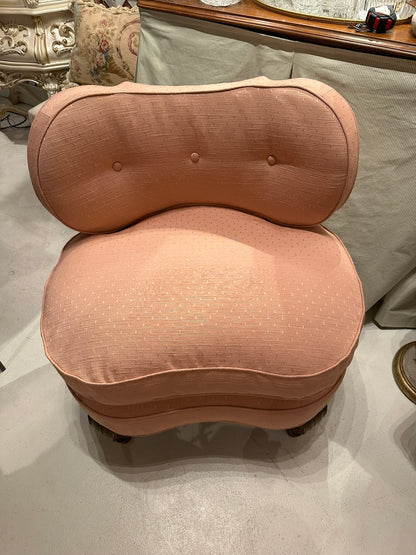 Antique pink coral boudoir chair, front view in showroom showing tufted back and curved seat