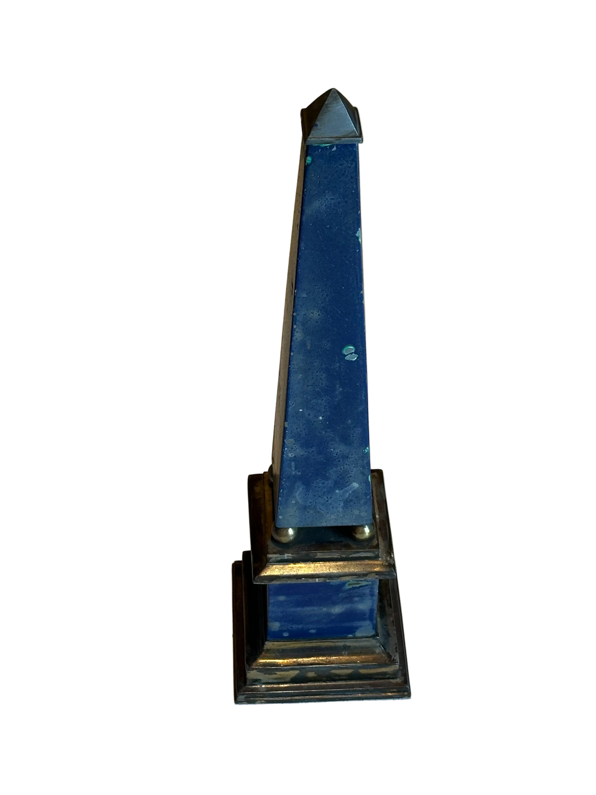 Tall blue faux-painted brass obelisk with pointed cap on stepped square base, angled