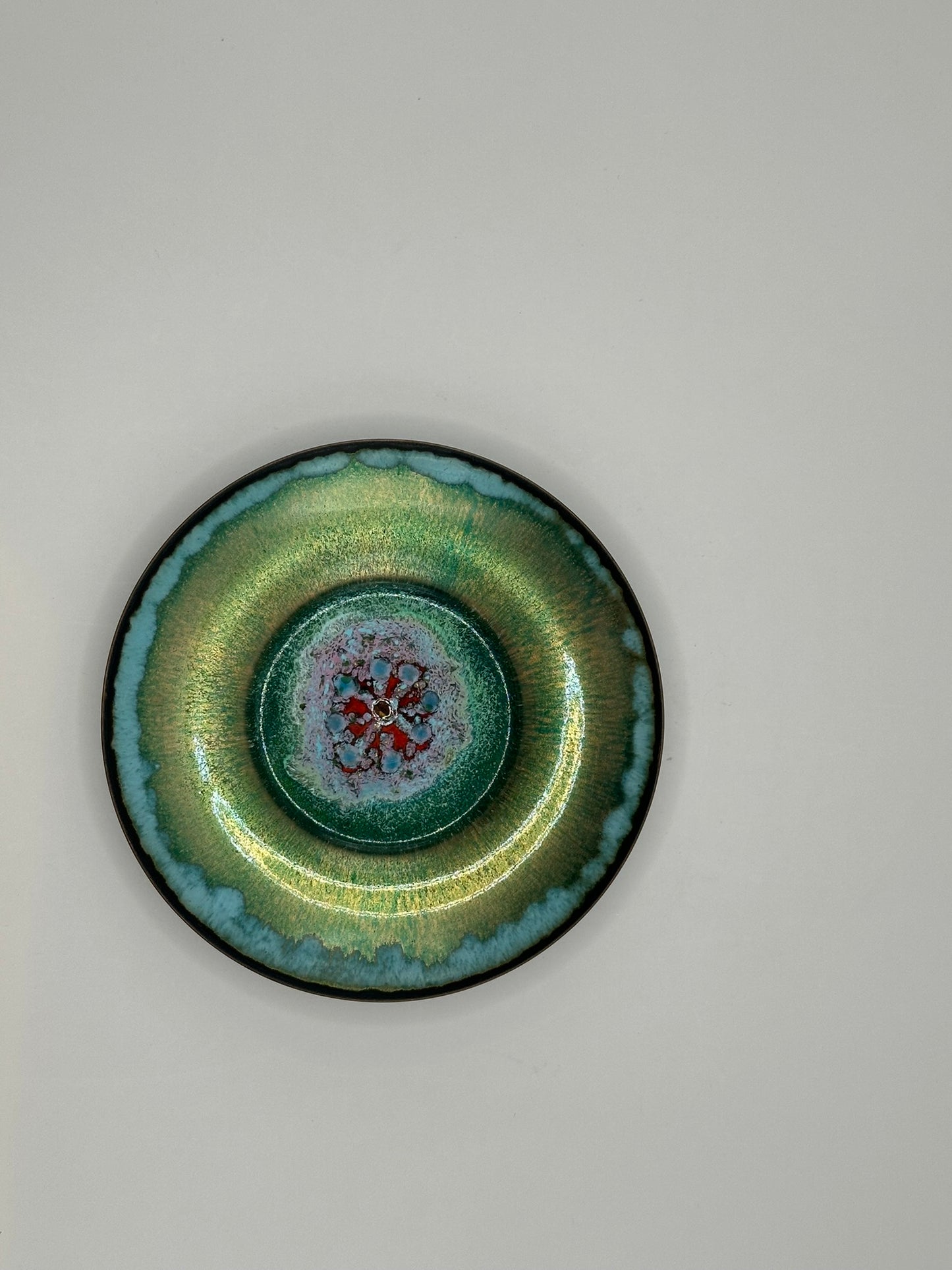Doris Hall petite green enamel-on-copper dish, overhead view of red floral starburst center