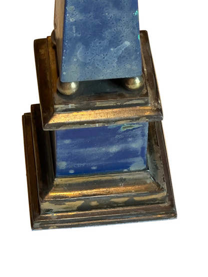 Close-up of blue faux-painted obelisk base showing brass ball accents and tarnished plinth