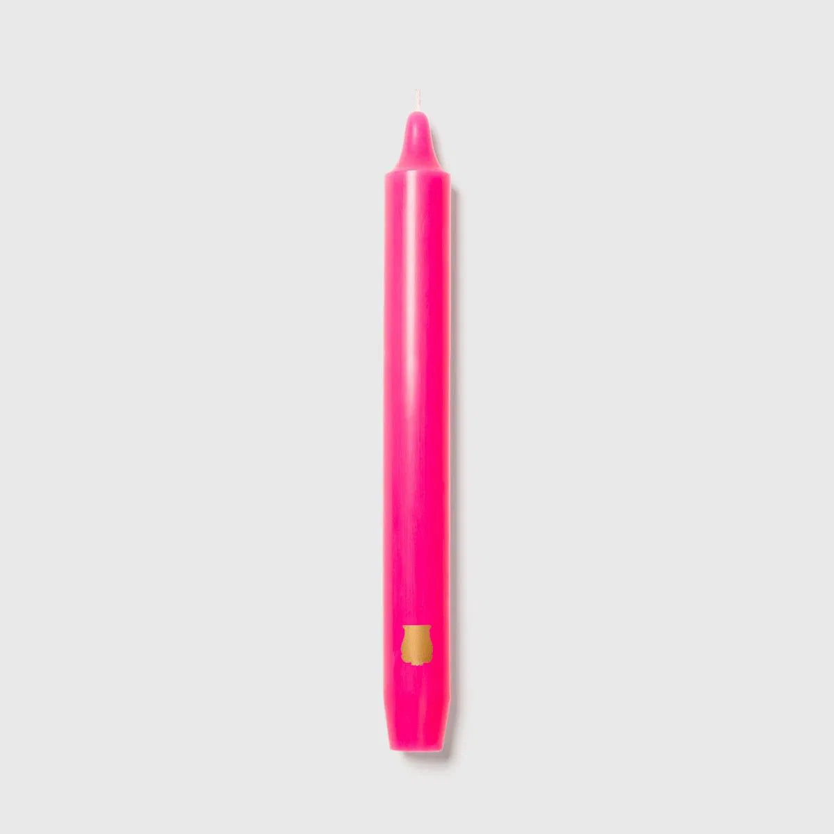 Fuchsia pink Trudon Madeleine taper candle upright with an embossed gold crest