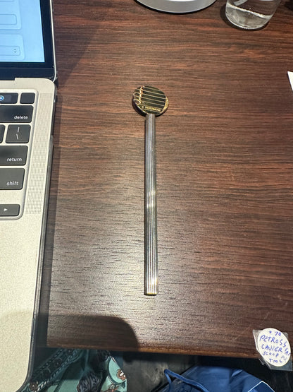 Full Petrossian caviar paddle spoon laid on a table, gilt paddle and long handle