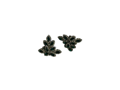 Vintage Les Bernard emerald green and rhinestone leaf-cluster clip earrings, angled view.