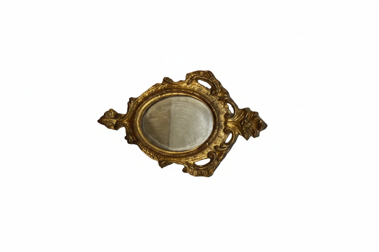 Florentine gilt oval mirror at an angle, highlighting the scrolled carved frame.
