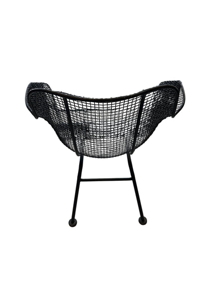 Rear view of black wire-mesh Russel Woodard chair on splayed iron legs