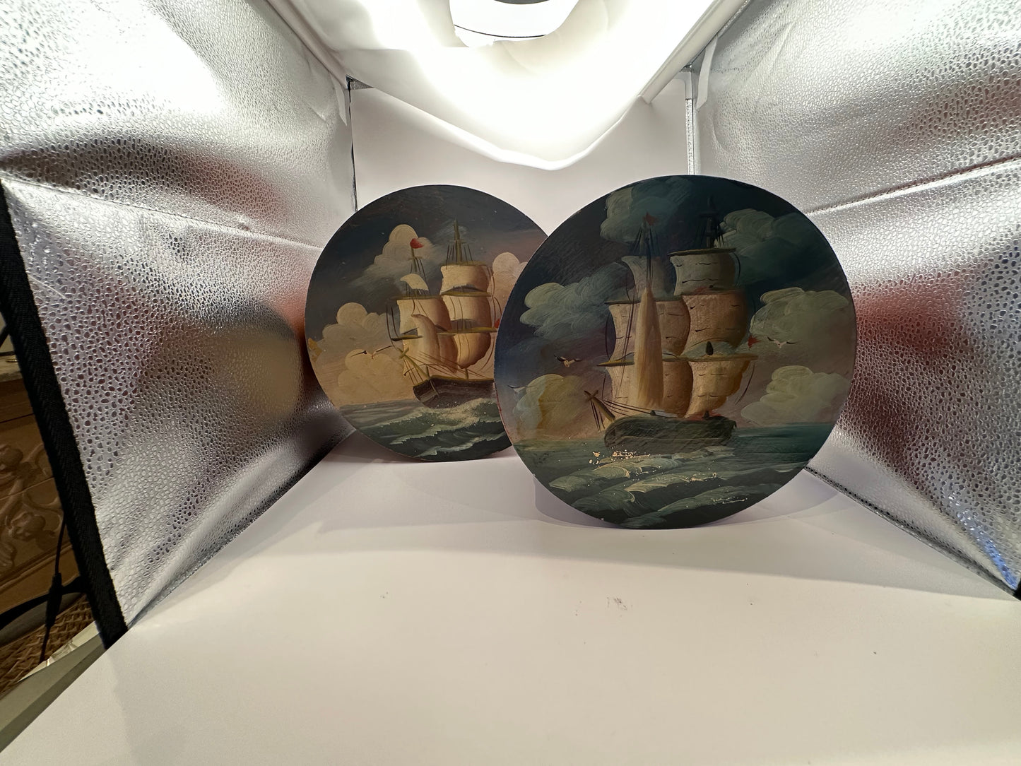 Two round box lids painted with sailing ships under cloudy skies