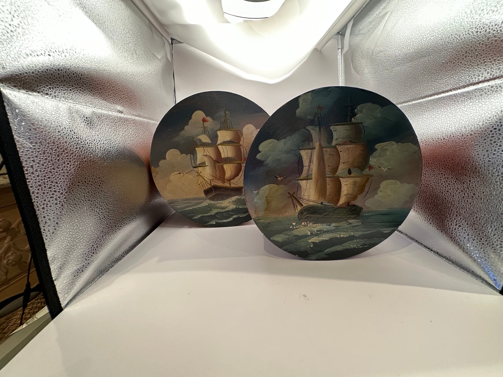 Two round box lids painted with sailing ships under cloudy skies
