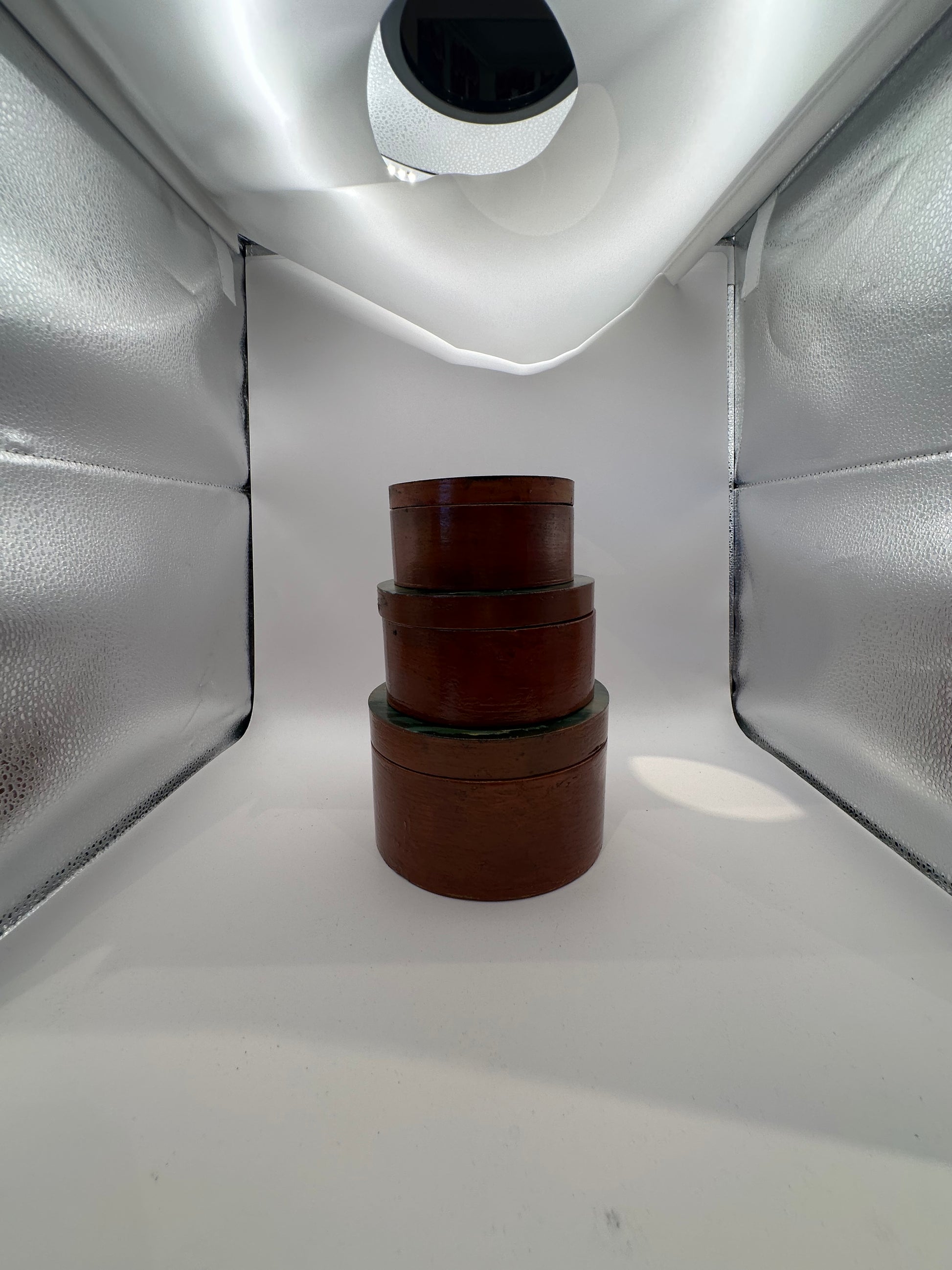 Nesting set of three reddish-brown round boxes with painted lids, front view