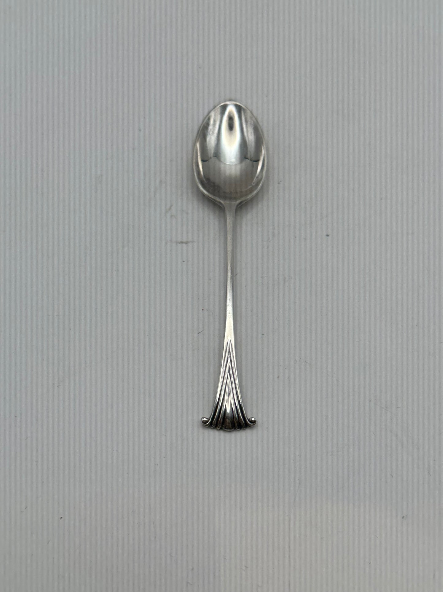 Single silverplate demitasse spoon, front view, oval bowl and slender handle with fanned scroll terminal