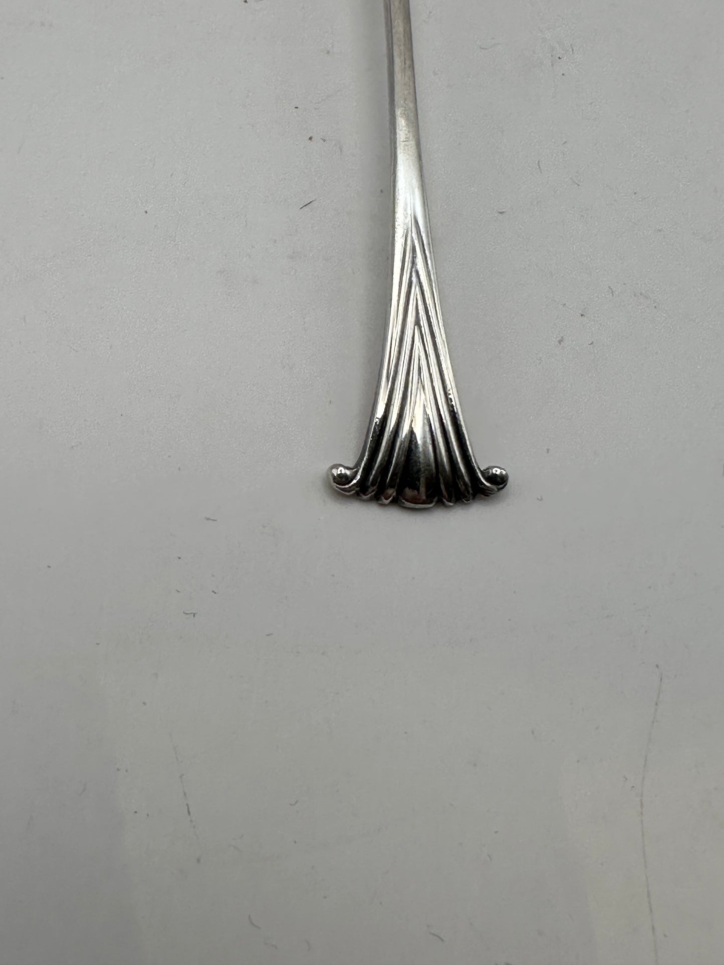 Close-up of the fanned scroll-shell terminal at the end of a silverplate demitasse spoon handle