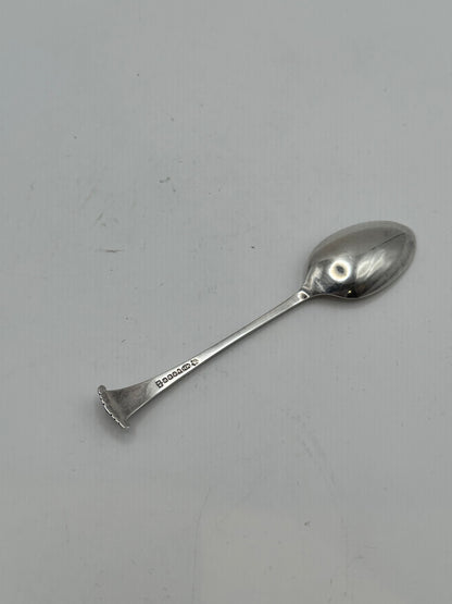 Single silverplate demitasse spoon shown at an angle, oval bowl and scroll-shell handle, with hallmarks on the stem