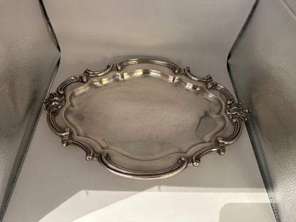 Vintage Rococo Revival silver plate oval tray with scrolled rim, angled view in light box