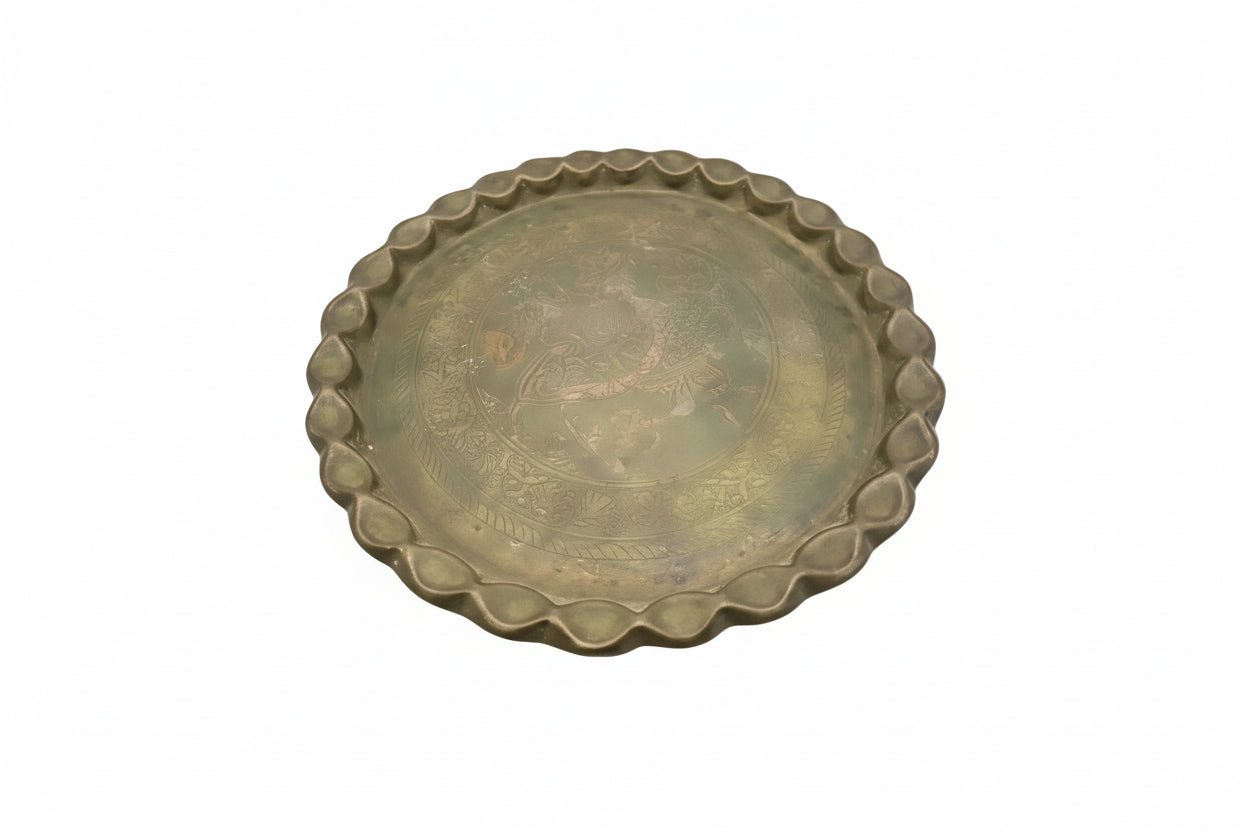 Vintage brass hammered tray with scalloped rim and engraved dragon center, angled view on white