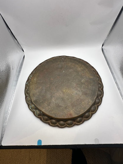 Vintage brass hammered tray top view in a light box, showing aged patina and scalloped rim