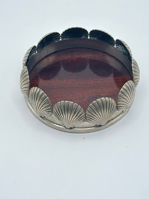 Angled view of MCM scallop shell silverplate bottle coaster with wood base