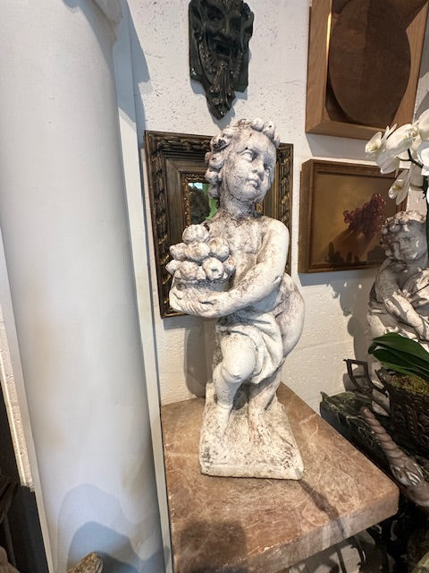 Vintage concrete Autumn cherub statue shown full length on a marble-topped stand