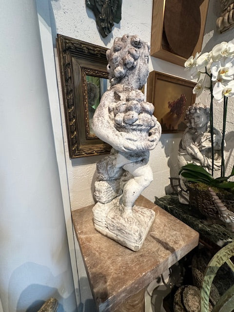 Concrete Autumn cherub statue, rear three-quarter view showing the back and rocky base