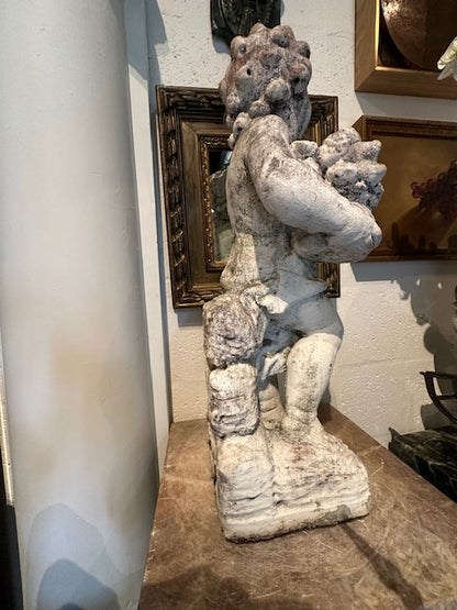 Concrete Autumn cherub statue viewed from behind, showing curled hair and textured base