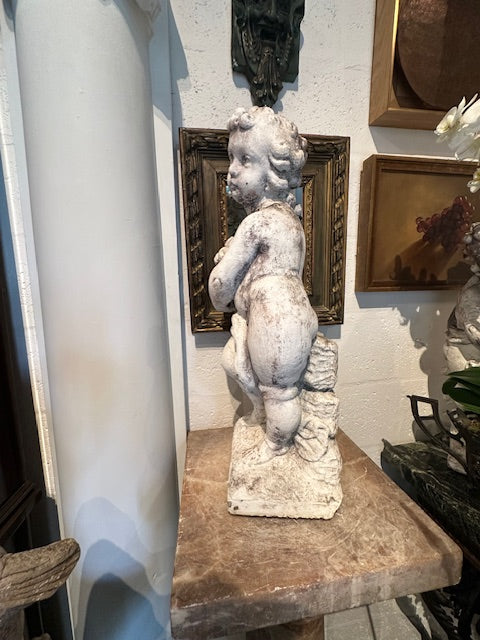 Close-up side view of the concrete cherub's curled hair and cradled basket of fruit