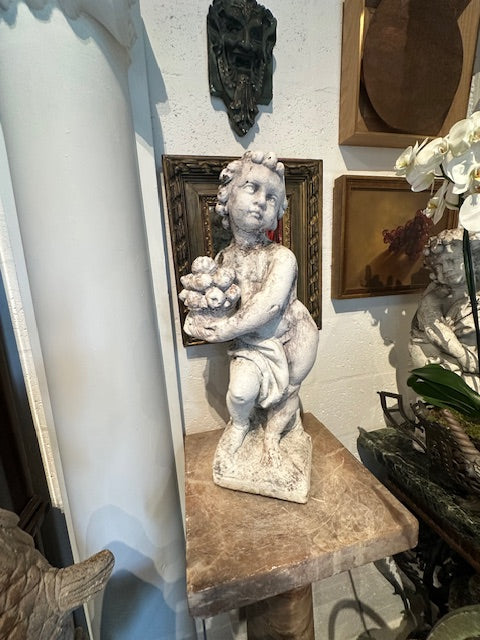 Concrete Autumn cherub statue, full front view on a marble-topped stand