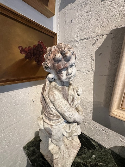 Concrete Four Seasons cherub statue displayed on green marble table in corner, angled view