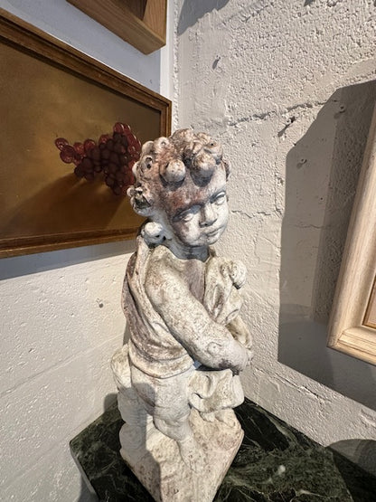 Concrete Four Seasons cherub statue displayed on green marble table in corner, angled view