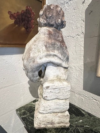 Side profile of concrete Four Seasons cherub statue on green marble table