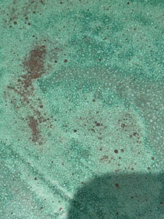 Macro detail of the speckled teal-green glaze surface with reddish-brown flecks.