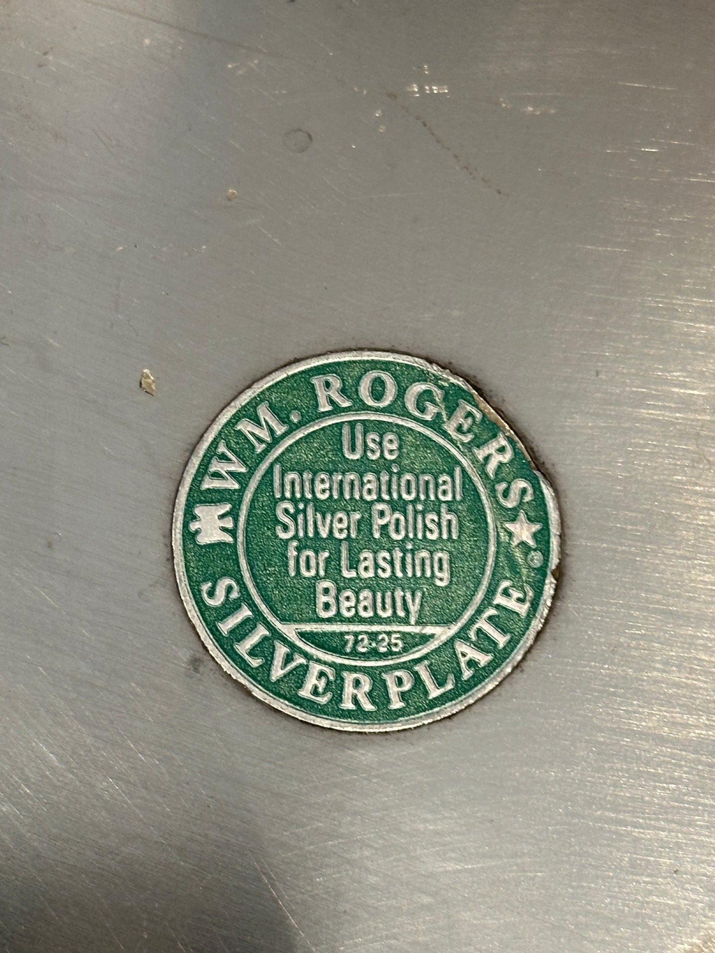 Close-up of green 'Wm. Rogers Silverplate' maker's label on bowl underside