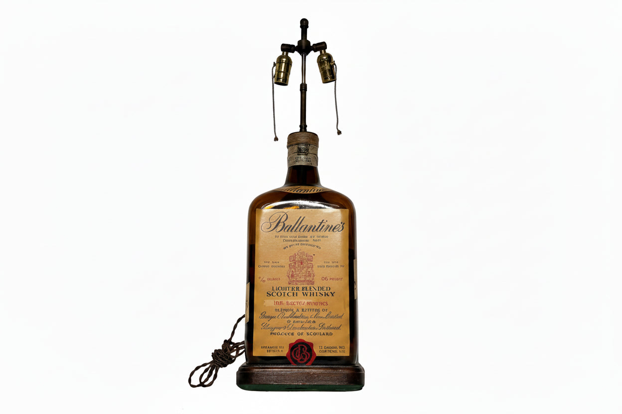 Vintage Ballantine's whiskey bottle table lamp, front view with twin brass sockets on a metal harp and wood base