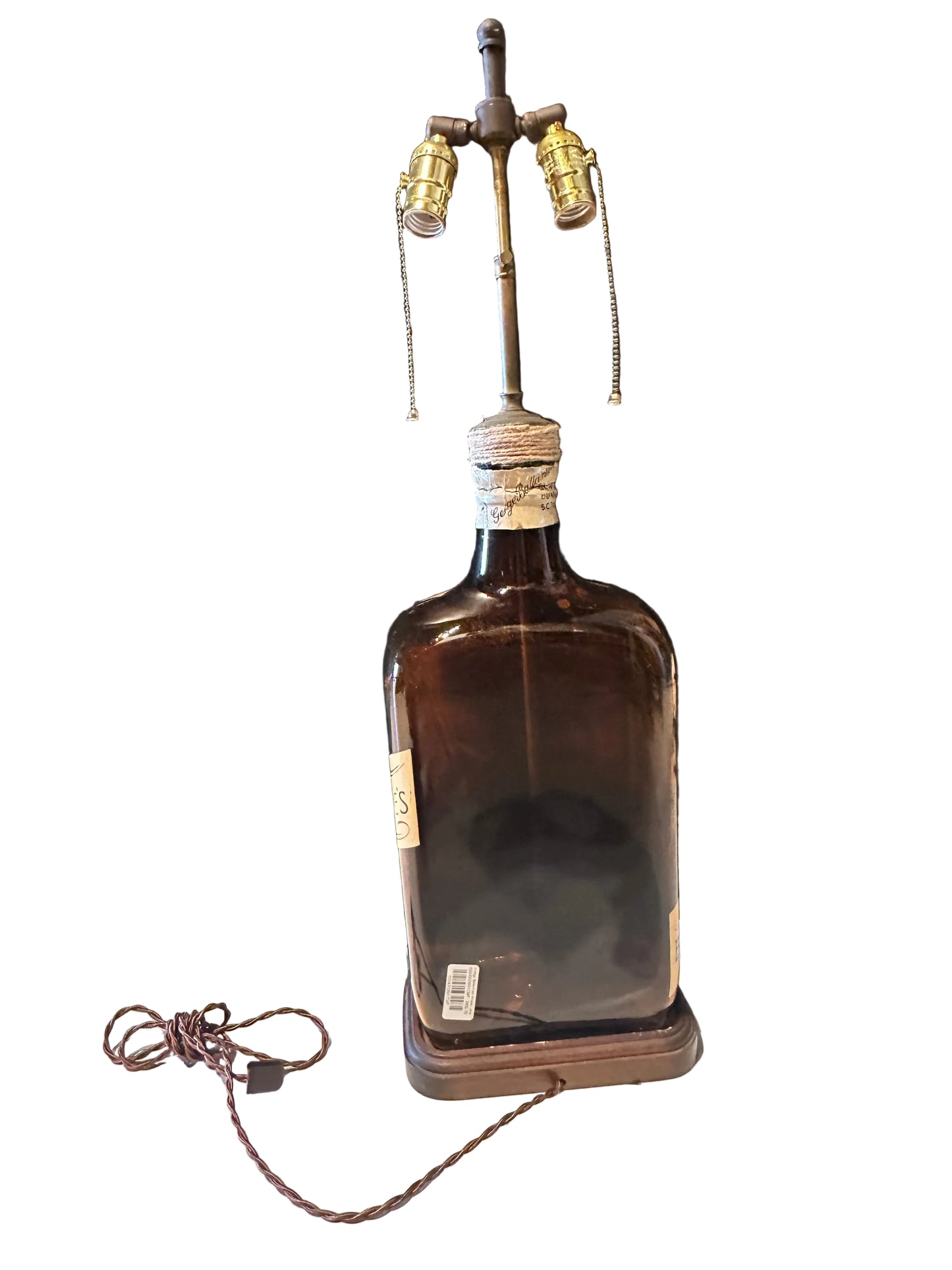 Back view of the amber bottle lamp showing twin sockets and cord-wrapped neck