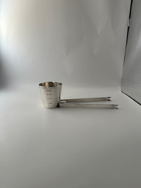 Napier silverplate bar tool on white, jigger cup upright with folding ice tongs extended to the side.