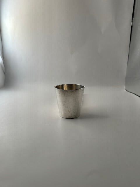 Napier silverplate jigger cup standing upright with the folding ice tongs tucked inside, front view.