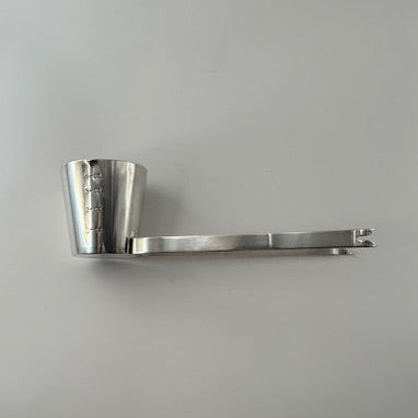 Top view of Napier silverplate jigger cup tilted to show its interior and the attached folding tongs.