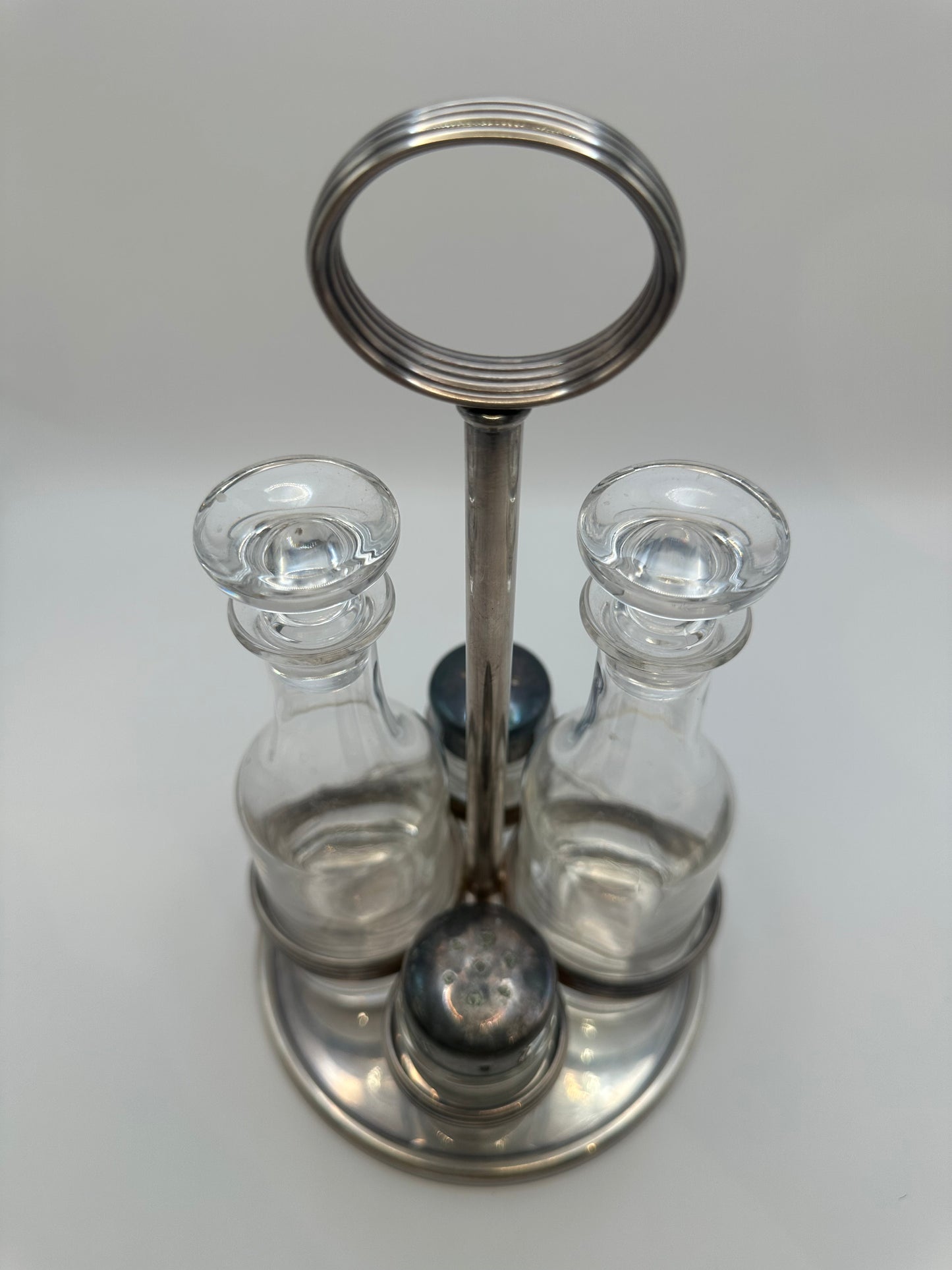 MCM silverplate cruet set from above showing dark shaker caps and glass stoppers.